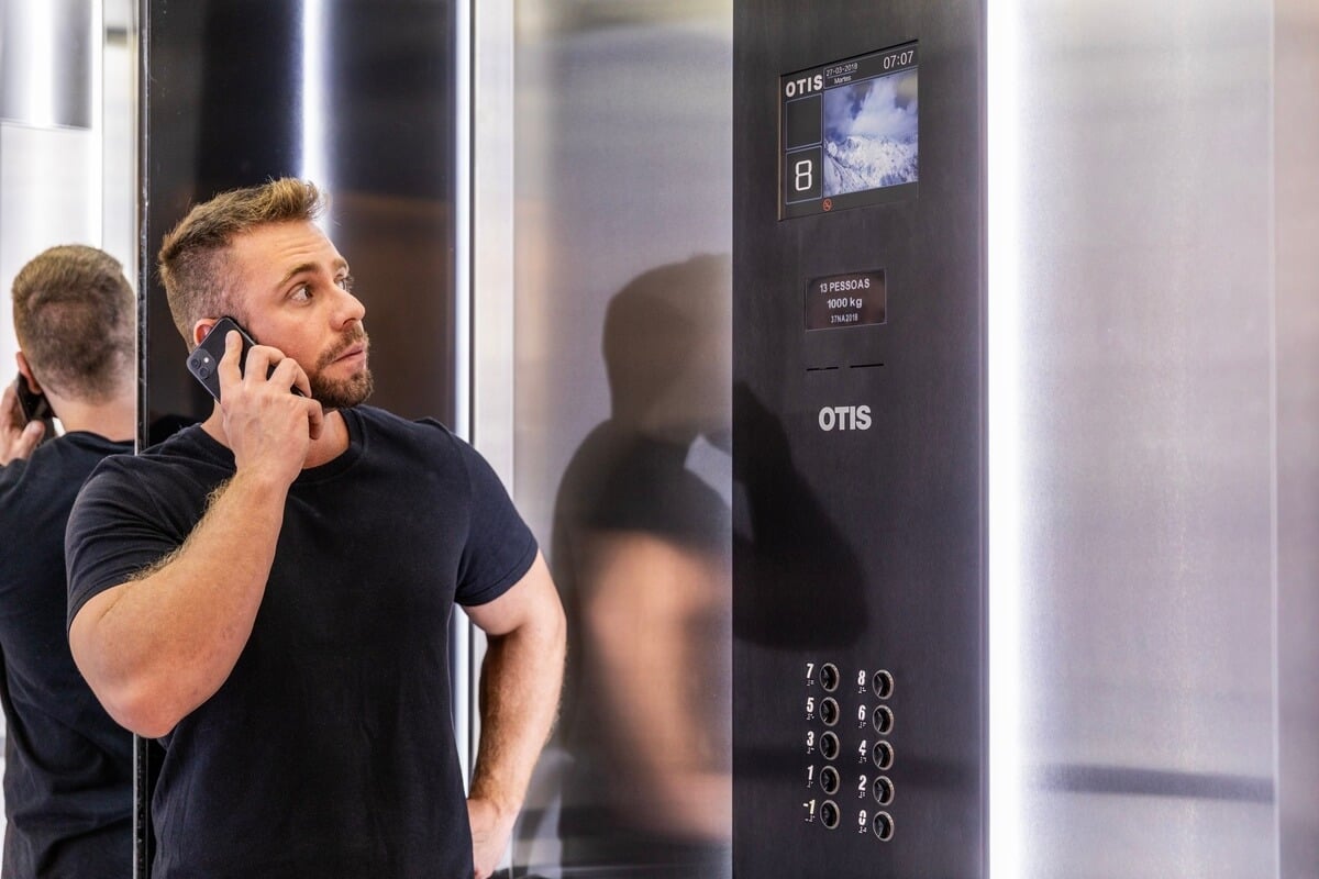 Homem usando celular dentro do elevador